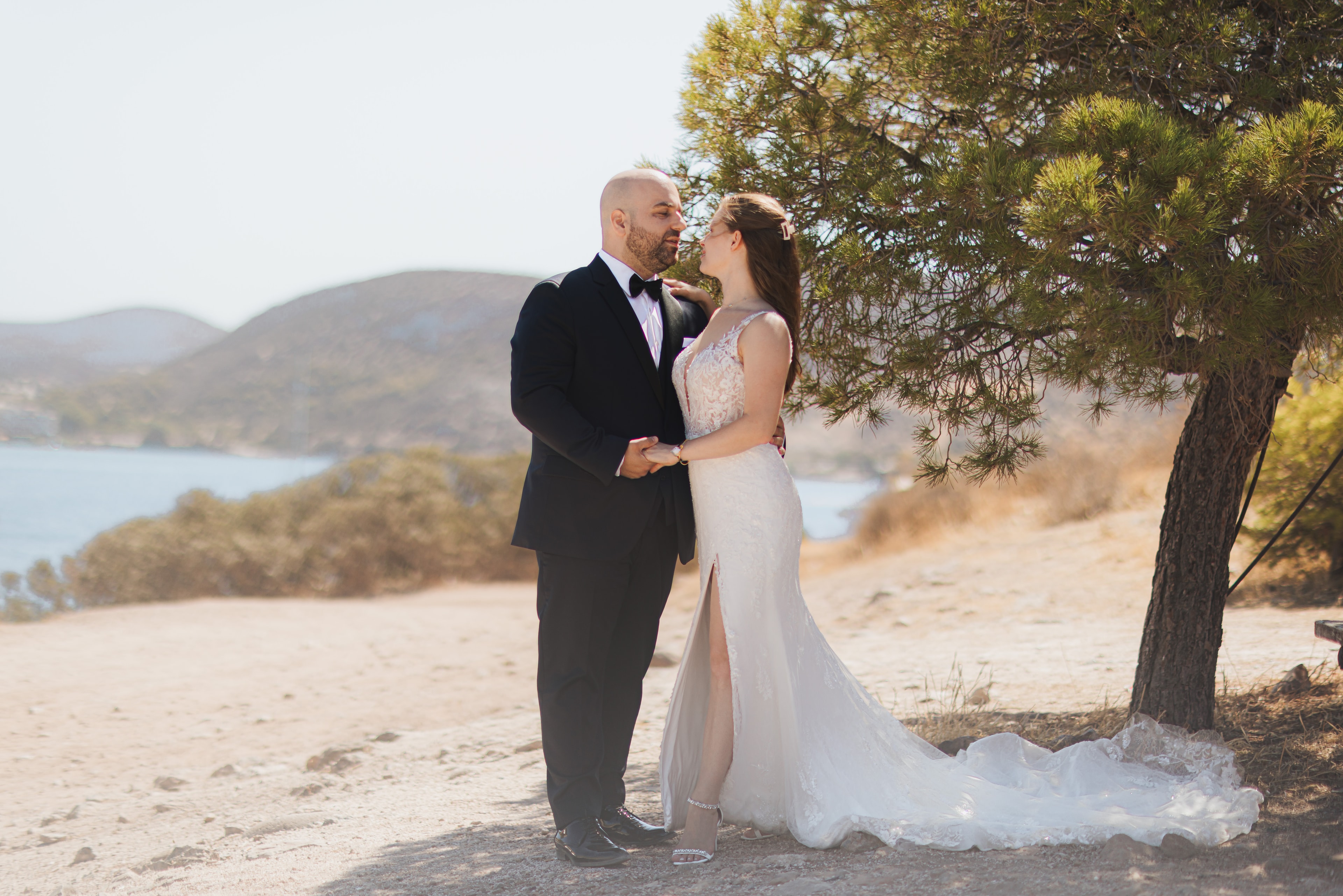Agis and Ioanna embracing beside a lakeside tree