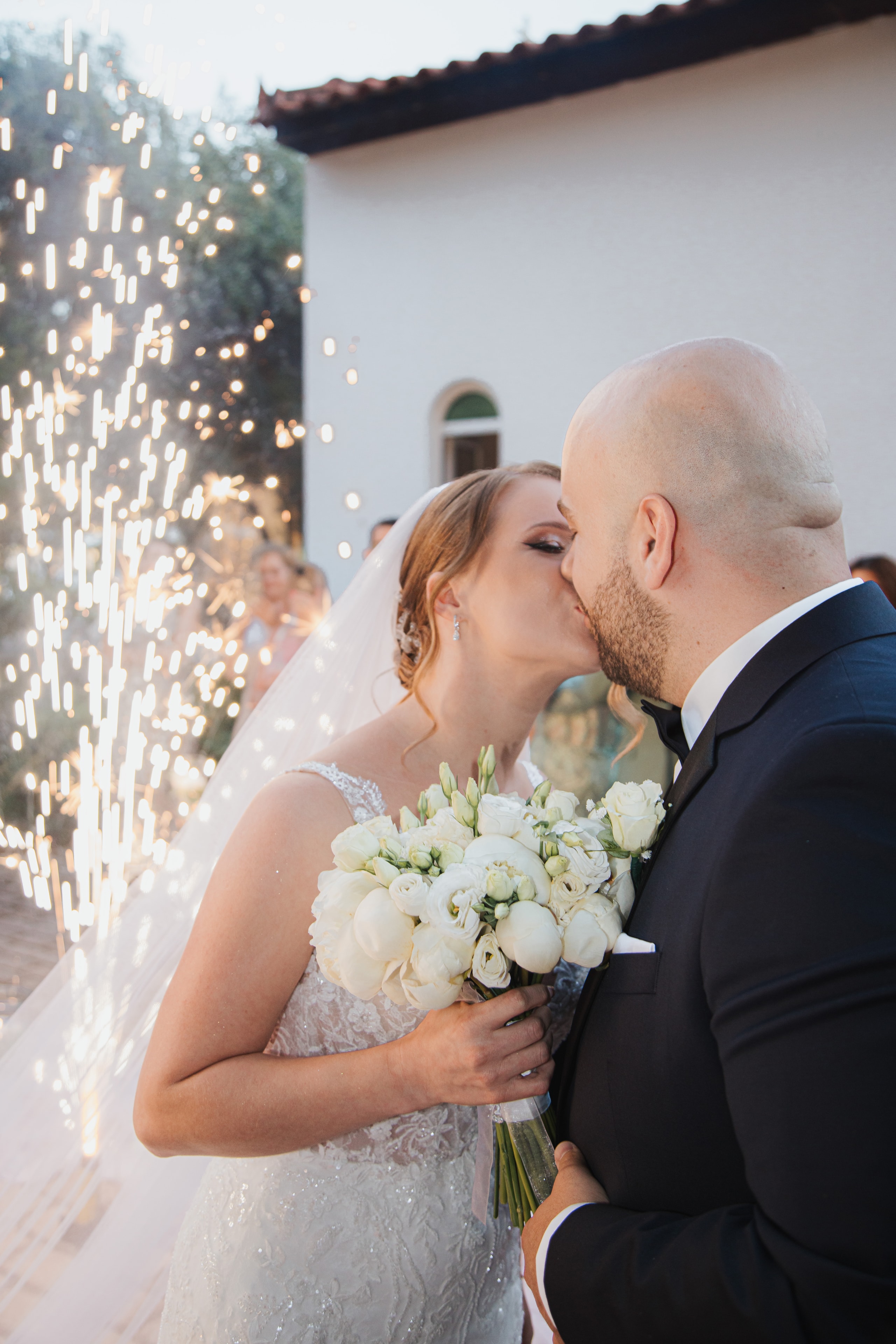 Agis and Ioanna kissing with sparklers at their reception