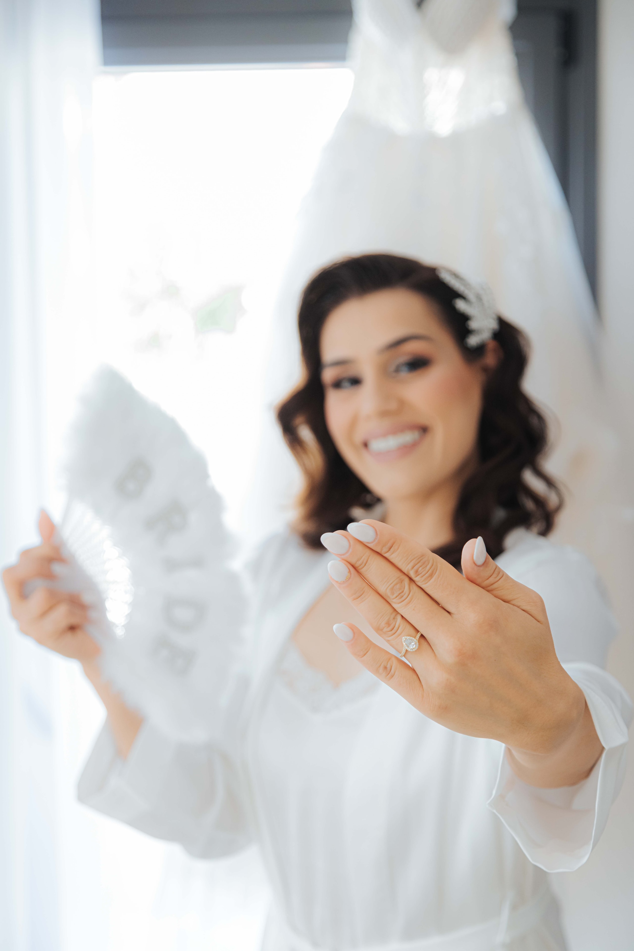 Varvara showing her engagement ring while holding a fan